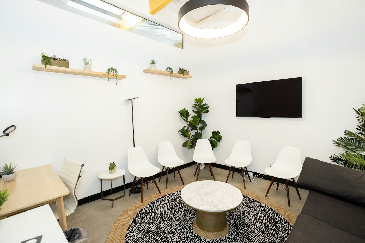 Ambiente profissional iluminado, com cadeiras, plantas e área de acolhimento